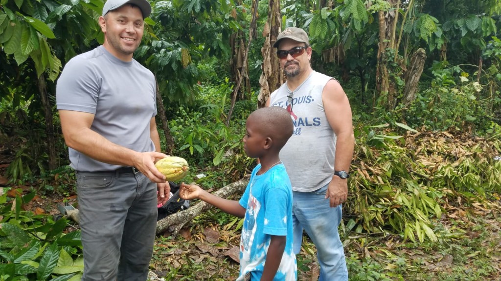 Cristian, one of the village boys,  giving Matt a pod of cocoa beans as a thank you gift.